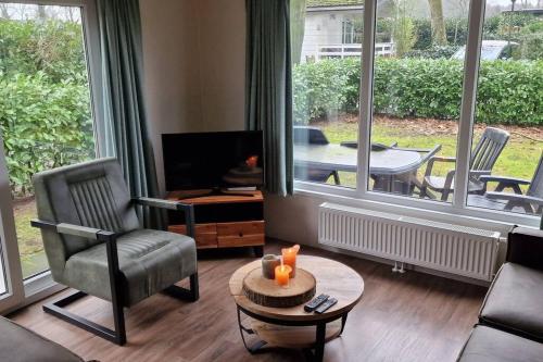 a living room with a couch and a chair and a table at Mooi chalet op prachtige plek in het groen in Voorthuizen