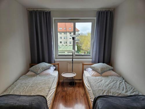 two beds in a room with a window at Apartament Stay with Gdynia in Gdynia