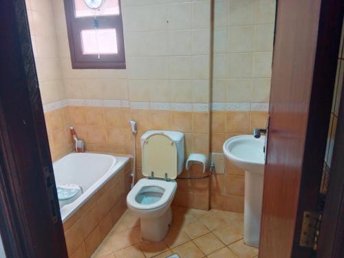 La salle de bains est pourvue de toilettes, d'une baignoire et d'un lavabo. dans l'établissement Family Studio Apartment, à Charjah