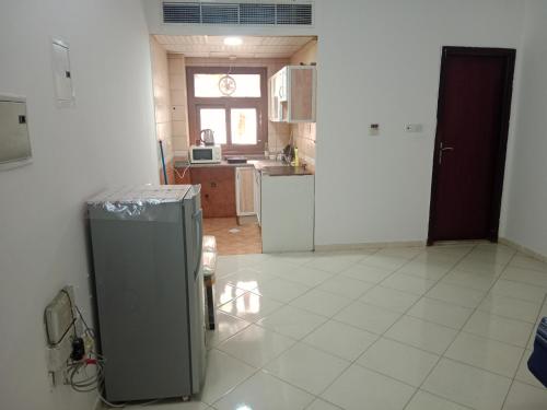a kitchen with a refrigerator in the middle of a room at Family Studio Apartment in Sharjah