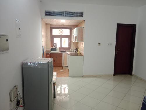 a kitchen with a refrigerator and a window at Family Studio Apartment in Sharjah