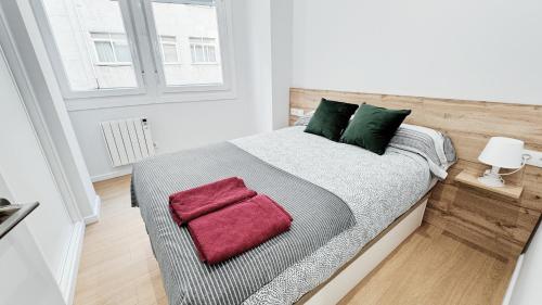 Schlafzimmer mit einem Bett mit grünen und roten Kissen in der Unterkunft Comodidad cerca de la playa.. a un paso de todo! in A Coruña