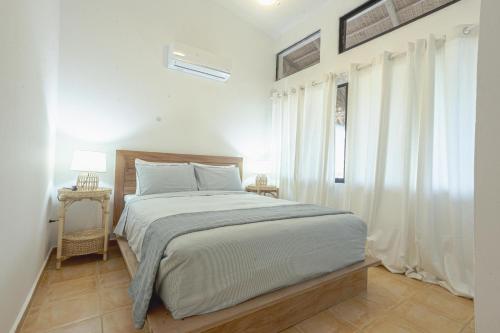 a white bedroom with a bed and a window at Surf Salvacion in San Felipe de Puerto Plata