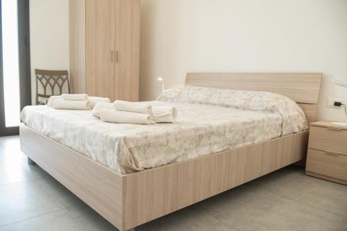 um quarto com uma grande cama de madeira com lençóis brancos em Villa Marica em Partinico