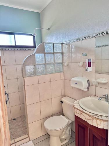 a bathroom with a toilet and a sink at Hotel La Fiore de Bahia in Uvita