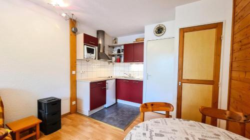 eine kleine Küche mit roten Schränken und einem Tisch in der Unterkunft Chalet De L'arbaron - Studio pour 4 Personnes 92 in Flaine