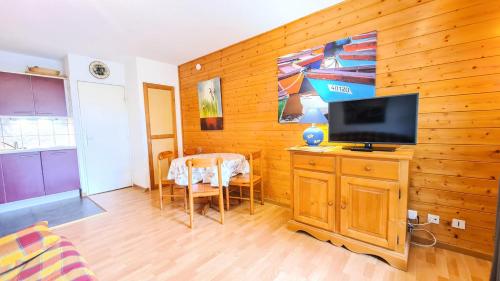 ein Wohnzimmer mit einem TV an einer Holzwand in der Unterkunft Chalet De L'arbaron - Studio pour 4 Personnes 92 in Flaine