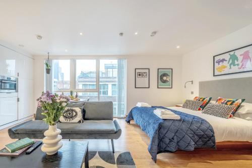 um quarto com uma cama, um sofá e uma mesa em Kula London - Tower Hill em Londres