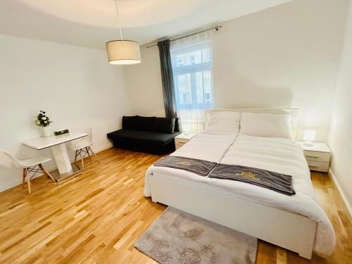 a bedroom with a white bed and a black couch at Helen Homestay 50m from Wenceslas Square in Prague