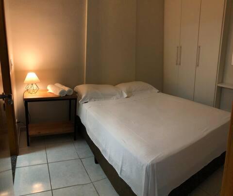 a bedroom with a bed and a table with a lamp at Studio 304 ao lado do Shopping e Metrô in Brasilia