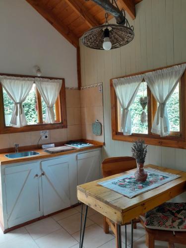 cocina con armarios blancos y mesa de madera en Casa de montaña Tierras del sur I en Villa La Angostura