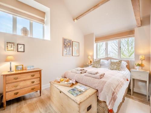 um quarto com uma cama, uma cómoda e janelas em The Woodshed em Lower Boddington