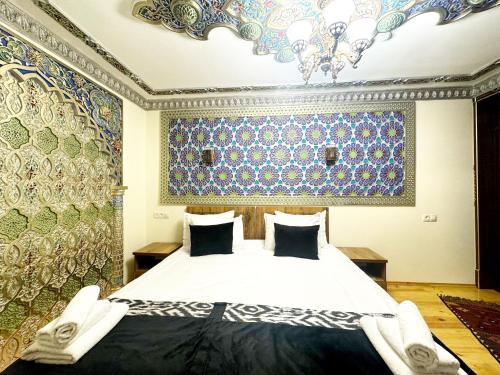 a bedroom with a bed and a ceiling with patterns at Bobosh Hotel in Bukhara