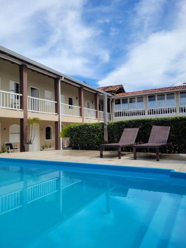 a swimming pool with two benches in front of a building at Pousada Jangadeiro in Porto Seguro