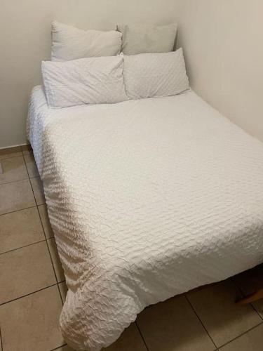 a bed with white sheets and pillows in a room at Rest Easy with 24/7 security in Cape Town