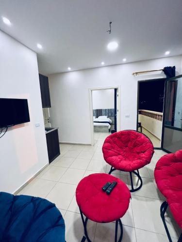 a living room with red chairs and a tv at Petra Heaven Boutique in Wadi Musa
