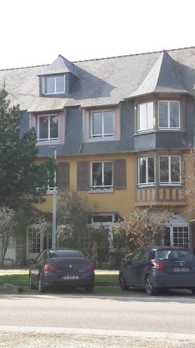 dos autos estacionados frente a una casa grande en Duplex Sables d'Or, en Fréhel