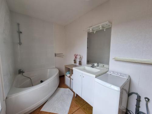 ein weißes Badezimmer mit einer Badewanne, einem Waschbecken und einem WC in der Unterkunft L Essentiel Appartement accueillant 5 pers 