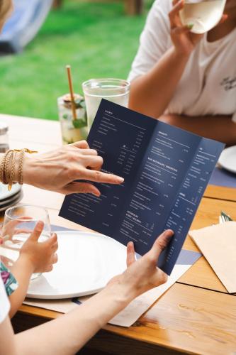a group of people sitting at a table holding a menu at Busola House in Stegna