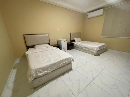 two beds in a room with white marble floors at مسكن الجنان للوحدات السكنية in Al Madinah