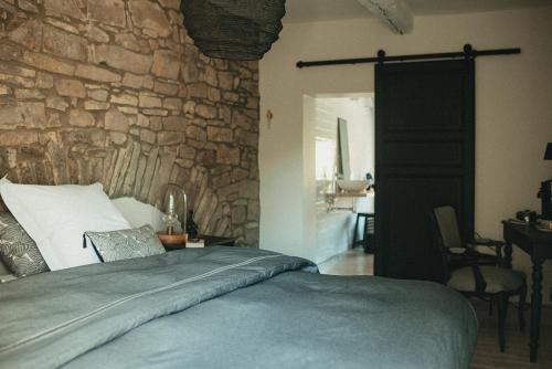 Un dormitorio con una pared de piedra y una cama en La Maison des Dames, 