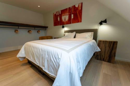 um quarto com uma cama grande e lençóis brancos em Wit Peerd Guesthouse em Londerzeel