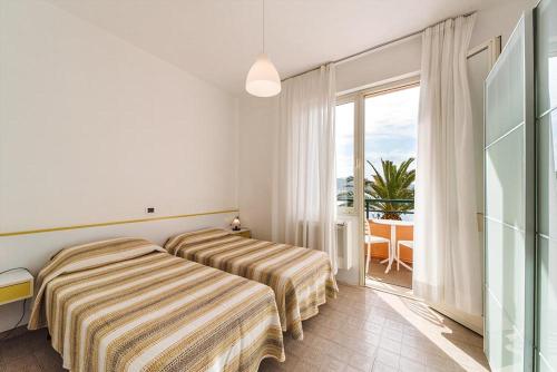 a hotel room with two beds and a balcony at Hotel Belmare in Porto Azzurro