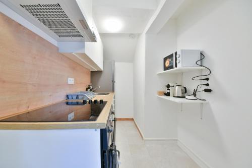 - une cuisine avec des murs blancs et un comptoir en bois dans l'établissement Pleasant Appartment near Stade de France, à Saint-Denis