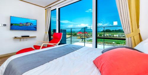 a bedroom with a bed and a large window at Boreum Pension in Seogwipo