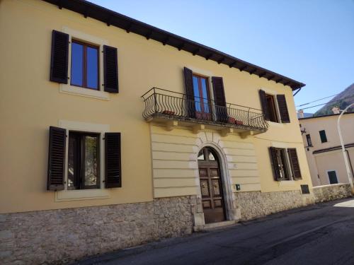 a yellow house with black shuttered windows and a balcony at Bed & Breakfast Costanza4 in Scanno