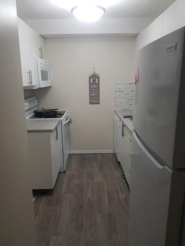 uma pequena cozinha com electrodomésticos brancos e pisos em madeira em Ron's Lodge em Saskatoon