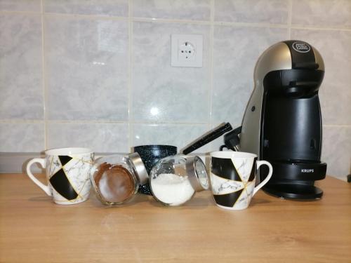 una fila de tazas de café en un mostrador junto a una cafetera en Mima studio en Kragujevac