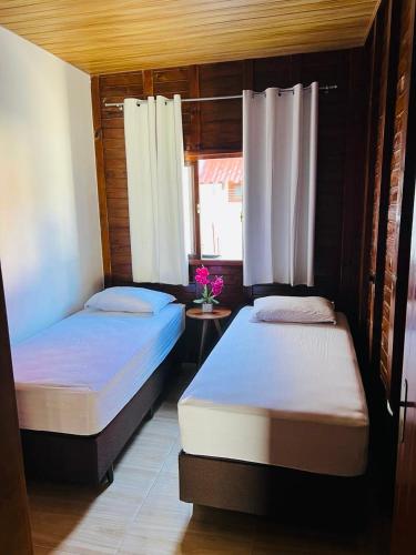 2 camas individuais num quarto com uma janela em Chalé Vila das Oliveiras em Penha