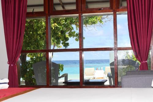 a room with a view of the beach through a window at Lagoon View Maldives in Bodufolhudhoo