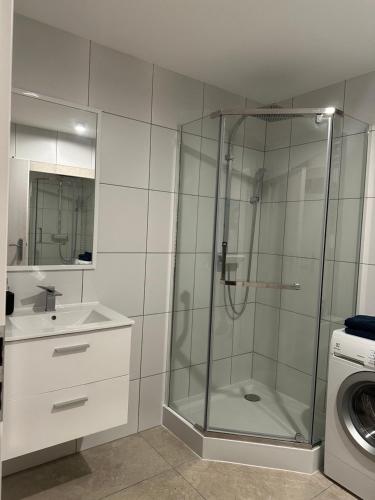 een badkamer met een douche, een wastafel en een wasmachine bij Guben Wohnungen in Guben