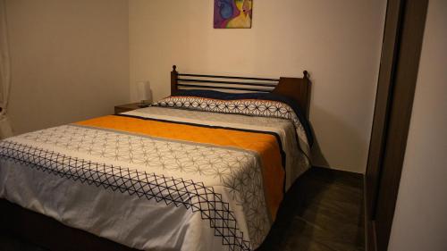 a bedroom with a bed with an orange and white comforter at Encantador cómodo y confortable. in Bogotá