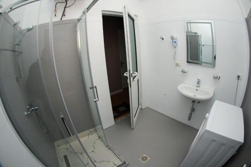 a bathroom with a shower and a sink and a mirror at Hotel Vila Alvin & Apartments in Sarandë