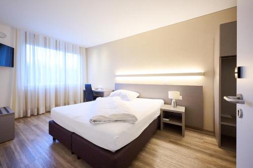 a hotel room with a bed and a window at Hotel am Kreisel Self-Check-In by Smart Hotels in Lachen