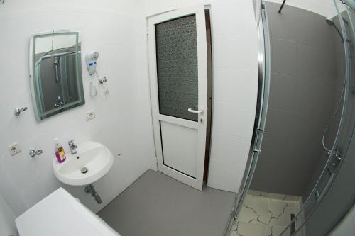 a white bathroom with a shower and a sink at Hotel Vila Alvin & Apartments in Sarandë