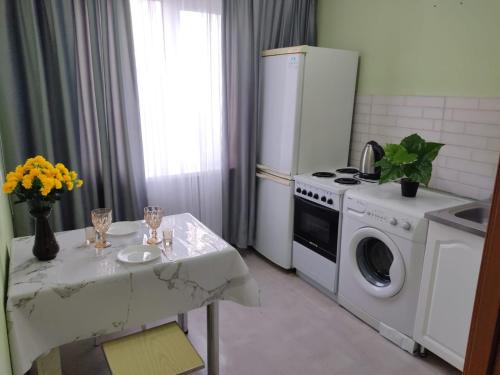 a kitchen with a table and a white refrigerator at Просторные 2-х комнатные апартаменты на 5 спальных мест in Ustʼ-Kamenogorsk