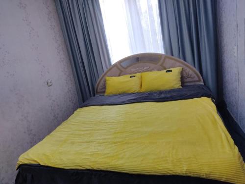 a bed with a yellow blanket and two yellow pillows at Просторные 2-х комнатные апартаменты на 5 спальных мест in Ustʼ-Kamenogorsk