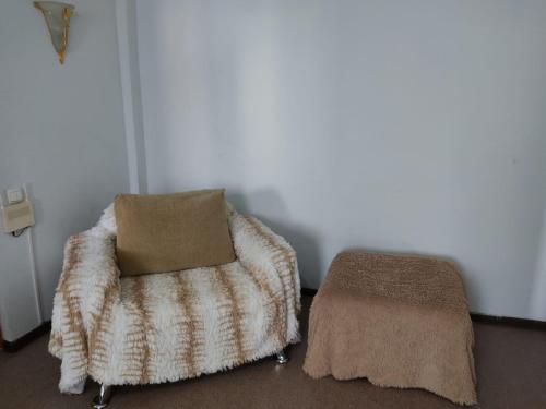 a room with a chair and a pillow and a ottoman at Просторные 2-х комнатные апартаменты на 5 спальных мест in Ustʼ-Kamenogorsk