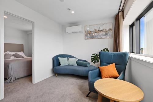 un soggiorno con una sedia blu e un tavolo di Golden Hotel a Christchurch