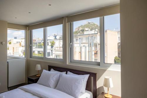 a bedroom with windows and a bed with white pillows at Penthouse in the heart of Athens in Athens