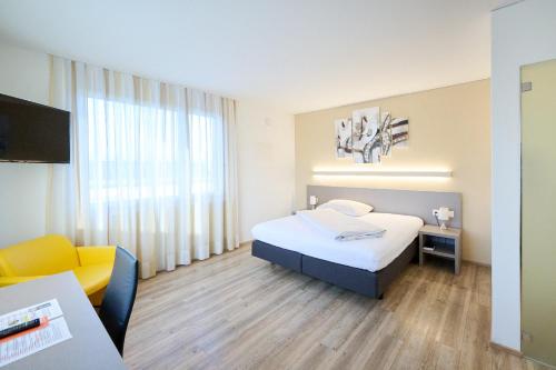 a hotel room with a bed and a chair and a television at Smart Hotel Kreisel --Self check-In in Lachen