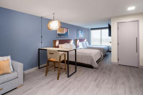 a bedroom with a bed and a desk with a table at Atwell Suites Austin Airport by IHG in Austin