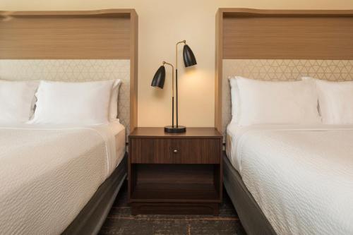 a hotel room with two beds and a lamp on a night stand at Holiday Inn Hotel & Suites Maple Grove Northwest Minneapolis-Arbor Lakes by IHG in Maple Grove