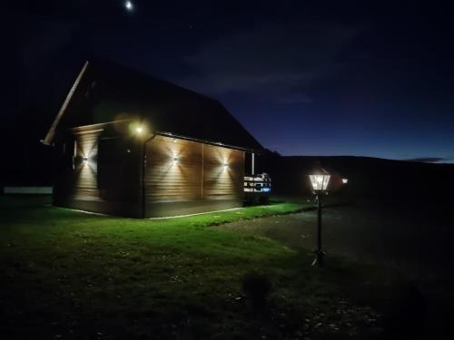 un granero de noche con luces encendidas en Domek Skitnica, en Mirsk