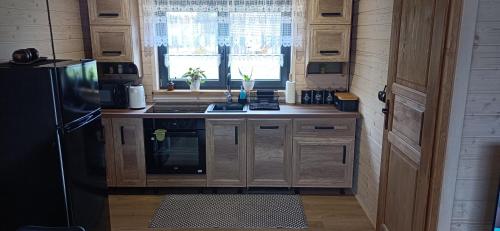 a kitchen with wooden cabinets and a black refrigerator at Domek Skitnica in Mirsk