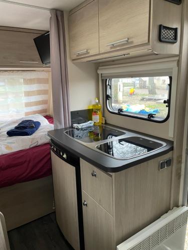 a kitchen in an rv with a sink and a bed at CAMPING LES HERLEQUINS in Losne